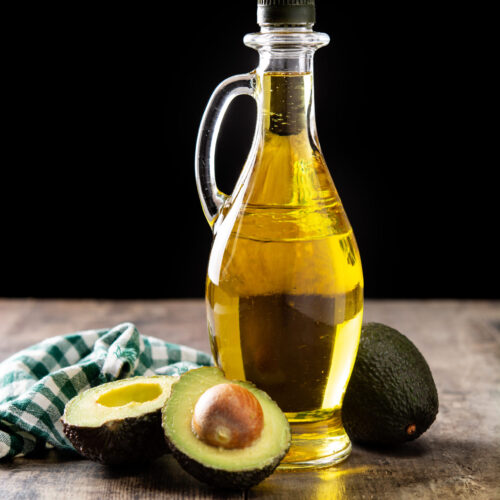 Oil and ripe fresh avocado on rustic wooden table